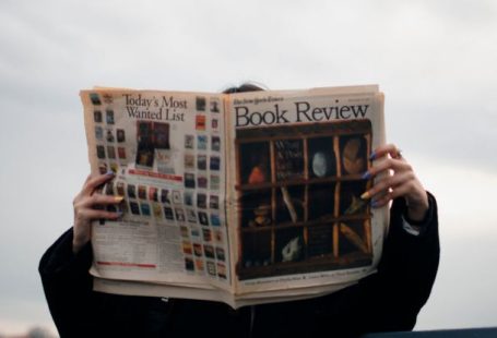 Review - Person Holding White and Brown Newspaper