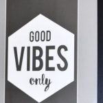 Philosophy - Picture in wooden frame with Good Vibes Only inscription hanging on white tiled wall