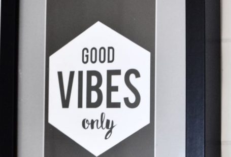 Philosophy - Picture in wooden frame with Good Vibes Only inscription hanging on white tiled wall
