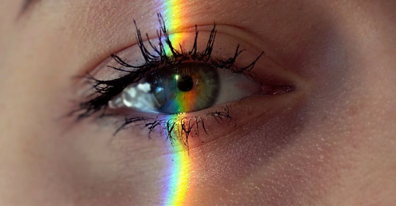 Mind-Body Problem - Closeup of crop anonymous sad female with green eyes and rainbow light on face looking at camera